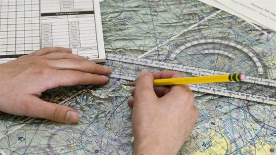 Hands plotting a cross-country route on a sectional chart